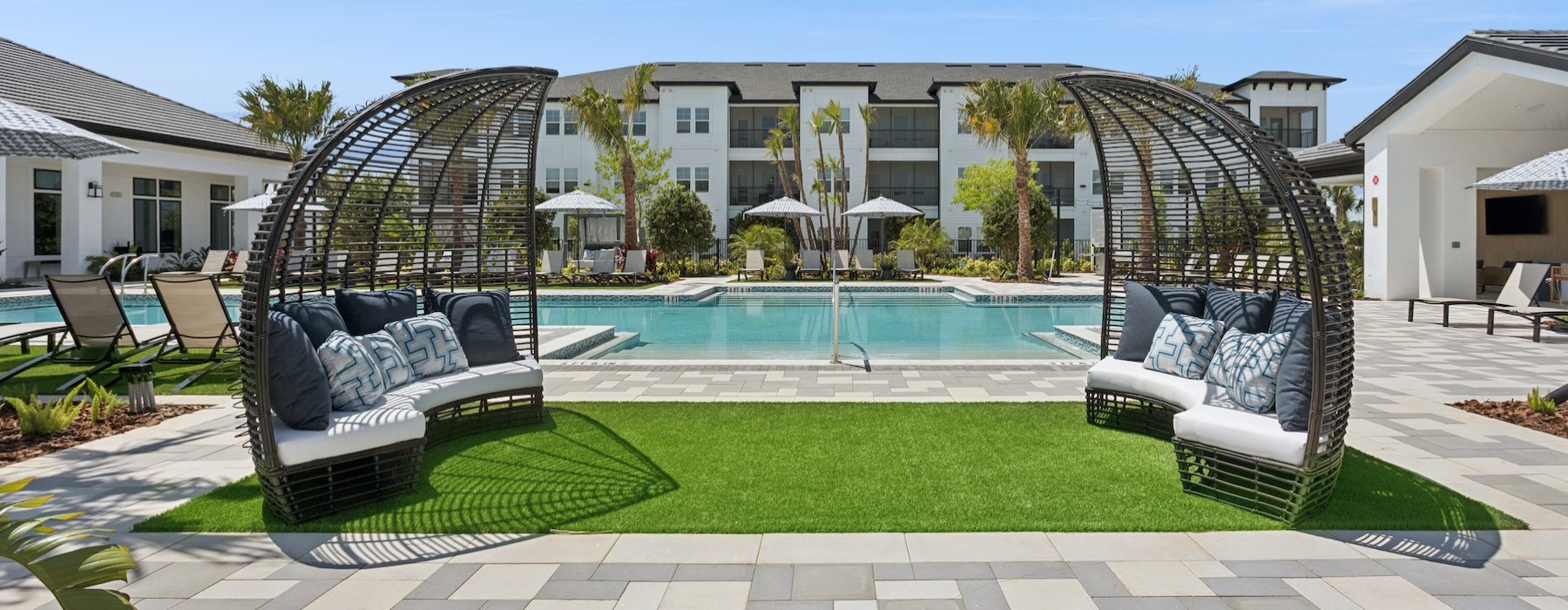 a swimming pool with chairs and a large building in the background