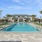 a swimming pool with palm trees and a building in the background